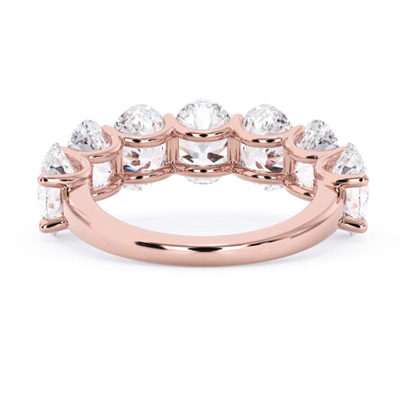 A picture of a seven stone diamond wedding ring with oval shaped diamonds that are U prong set in rose gold on a white background with a view of the underside of the ring.
