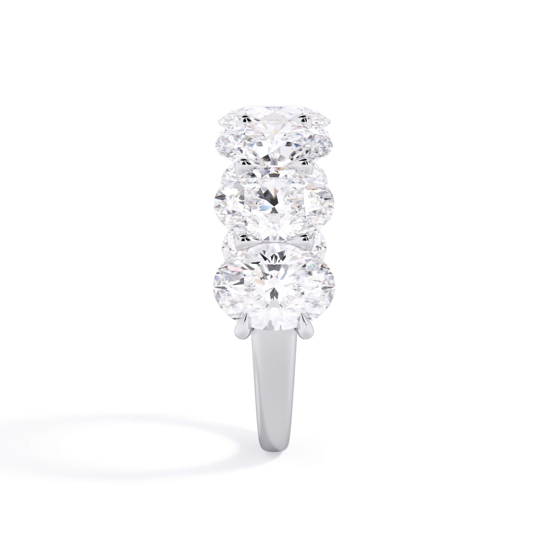 A picture of a seven stone diamond wedding ring with oval shaped diamonds that are U prong set in white gold or platinum on a white background with a side profile view.