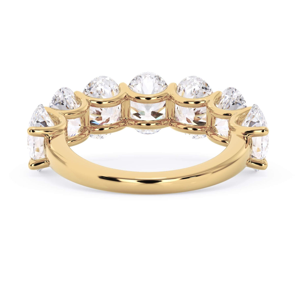 A picture of a seven stone diamond wedding ring with oval shaped diamonds that are U prong set in yellow gold on a white background with a view of the underside of the ring.