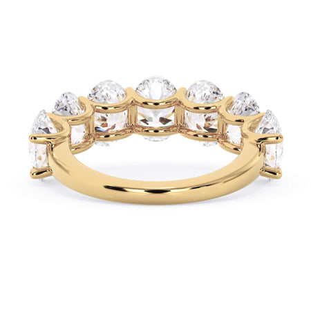 A picture of a seven stone diamond wedding ring with oval shaped diamonds that are U prong set in yellow gold on a white background with a view of the underside of the ring.