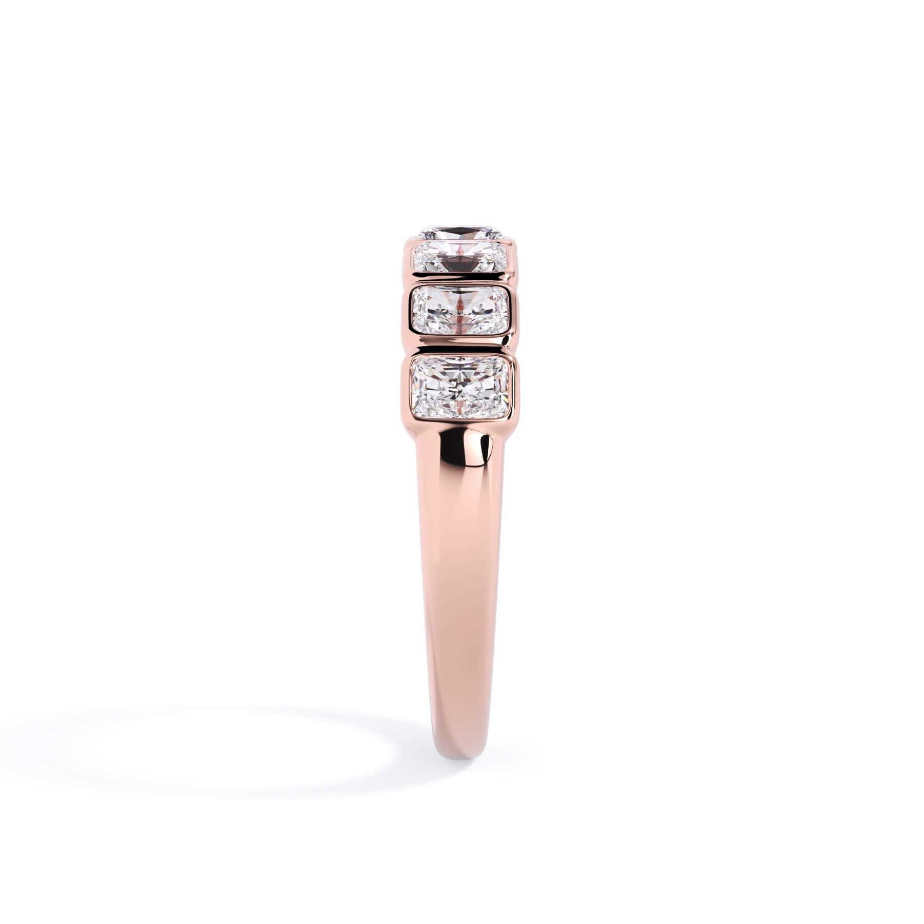 A picture of a seven stone diamond wedding ring with radiant cut diamonds that are bezel set in rose gold on a white background with the ring facing forward, lying down.