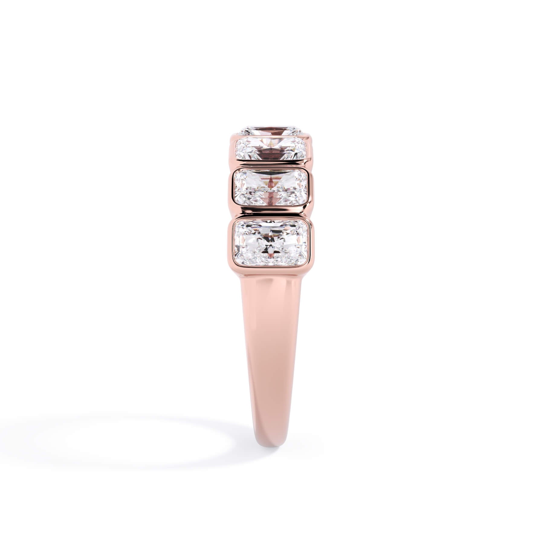 A picture of a seven stone diamond wedding ring with radiant cut diamonds that are bezel set in rose gold on a white background with a side profile view.