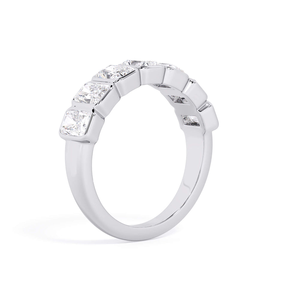 A picture of a seven stone diamond wedding ring with radiant cut diamonds that are bezel set in white gold or platinum on a white background with a slightly angled, through the finger view.