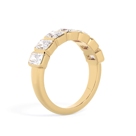 A picture of a seven stone diamond wedding ring with radiant cut diamonds that are bezel set in yellow gold on a white background with a slightly angled, through the finger view.