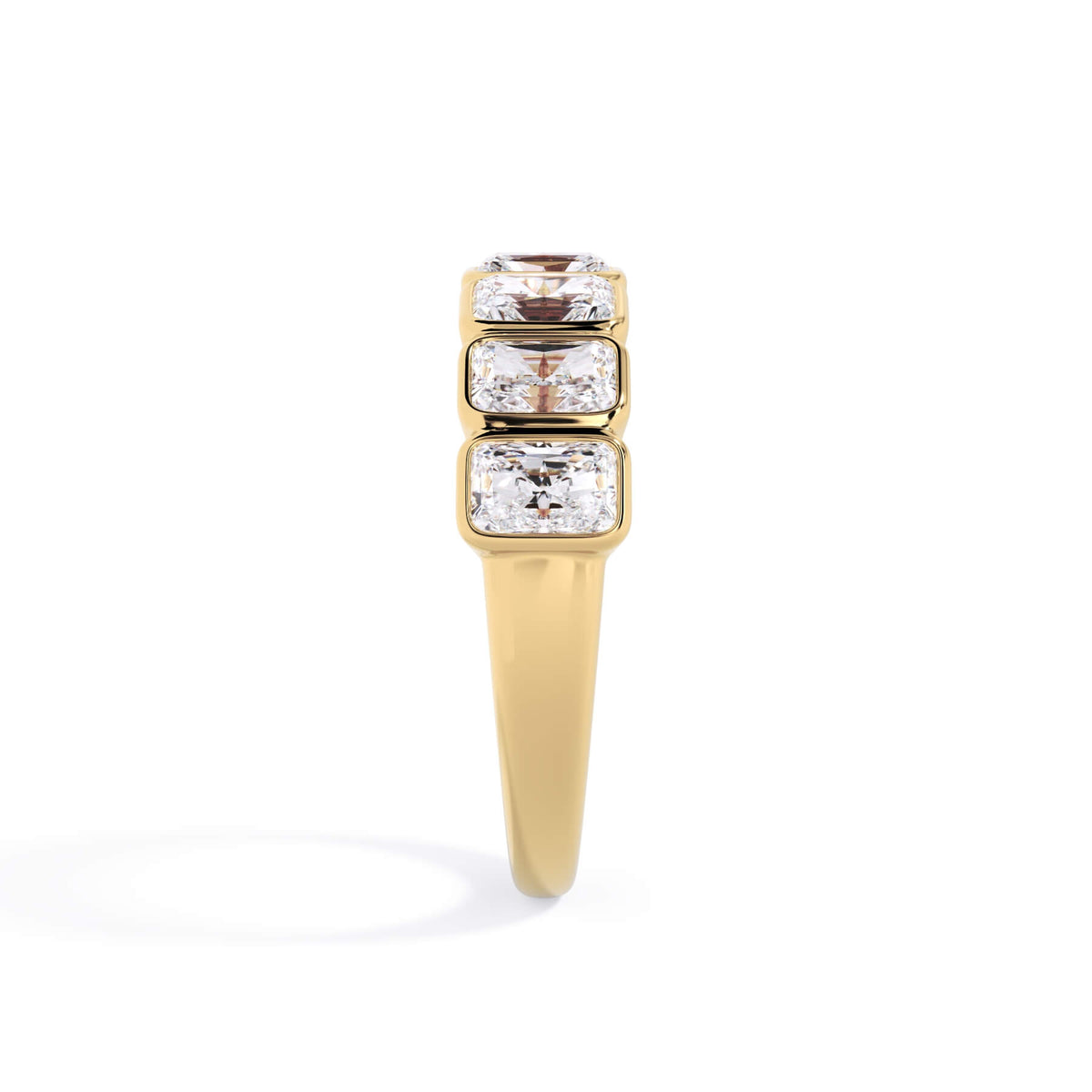 A picture of a seven stone diamond wedding ring with radiant cut diamonds that are bezel set in yellow gold on a white background with a side profile view.