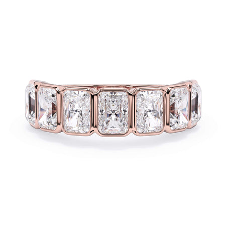 A picture of a seven stone diamond wedding ring with radiant cut diamonds that are bezel set in rose gold on a white background with the ring facing forward, lying down.