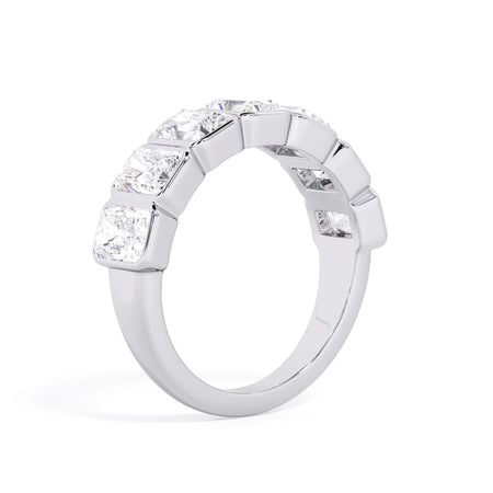 A picture of a seven stone diamond wedding ring with radiant cut diamonds that are bezel set in white gold or platinum on a white background with a slightly angled, through the finger view.