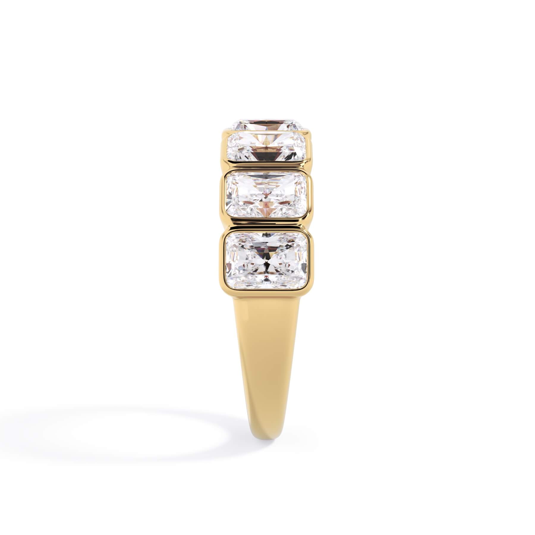 A picture of a seven stone diamond wedding ring with radiant cut diamonds that are bezel set in yellow gold on a white background with a side profile view.