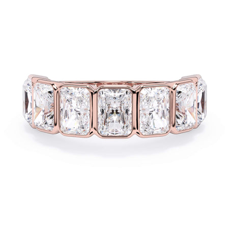 A picture of a seven stone diamond wedding ring with radiant cut diamonds that are bezel set in rose gold on a white background with the ring facing forward, lying down.