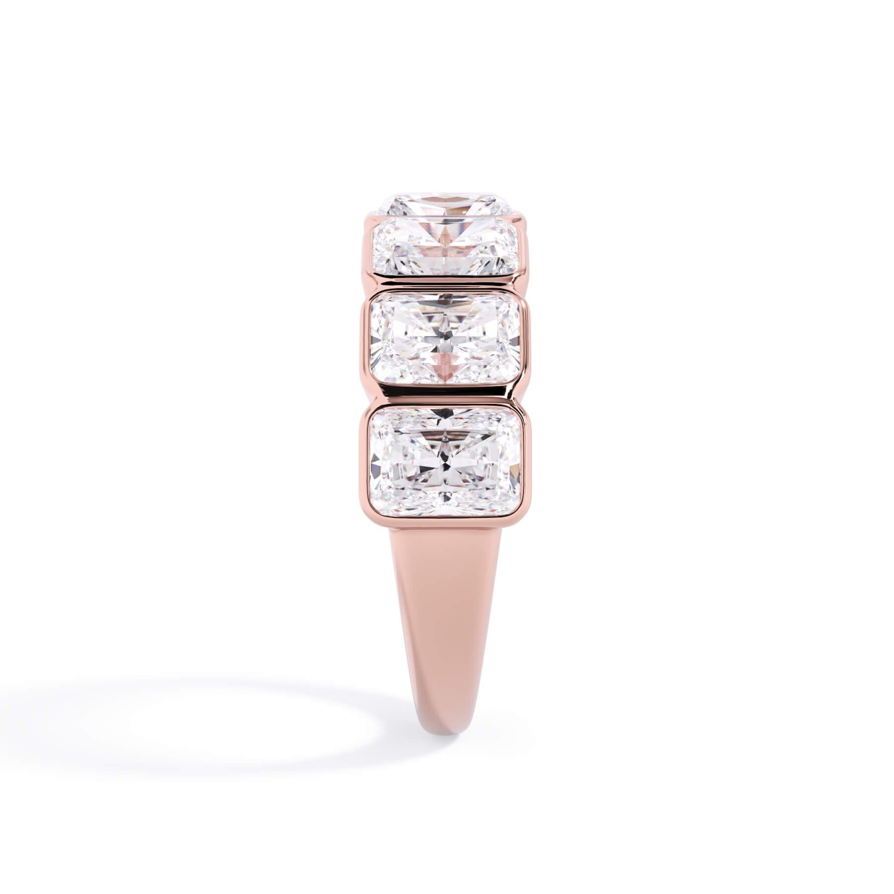 A picture of a seven stone diamond wedding ring with radiant cut diamonds that are bezel set in rose gold on a white background with a side profile view.
