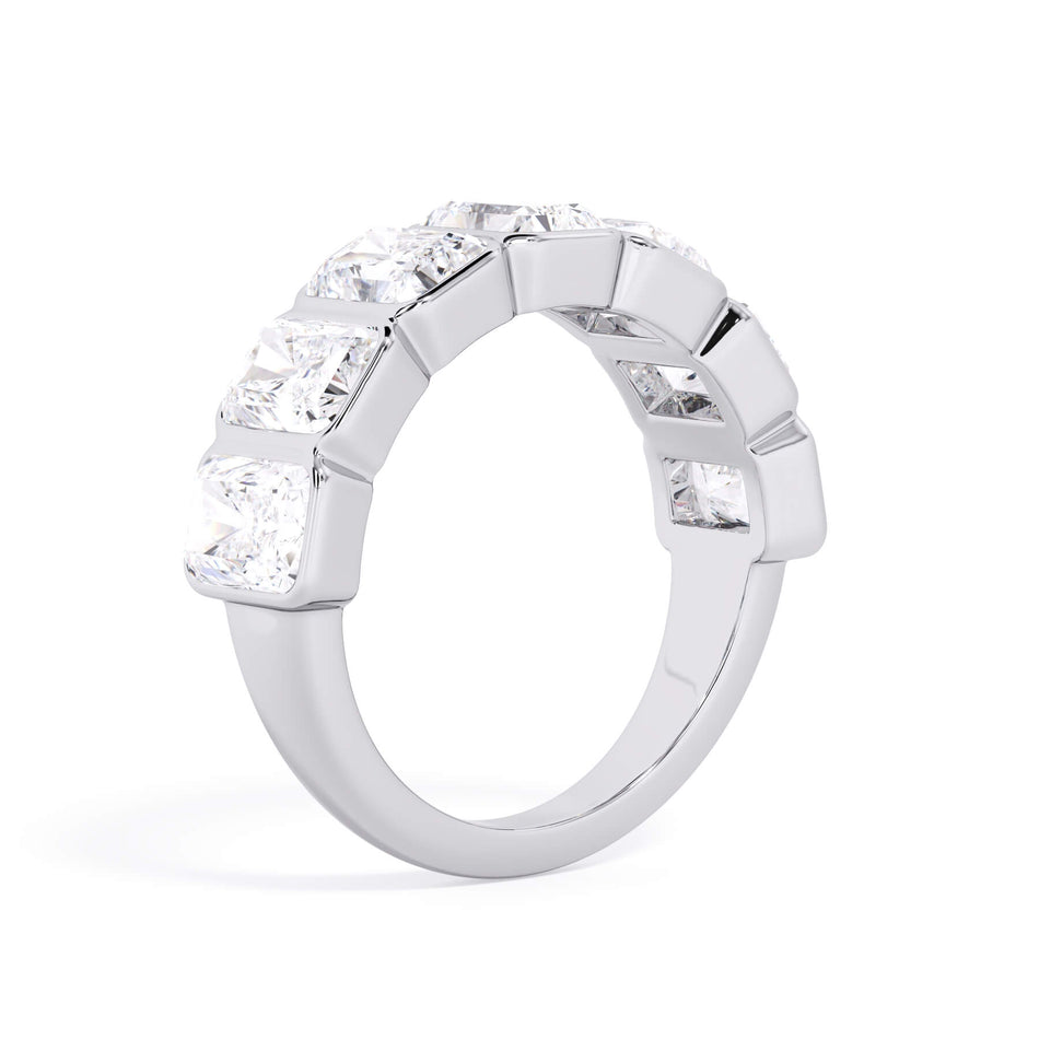 A picture of a seven stone diamond wedding ring with radiant cut diamonds that are bezel set in white gold or platinum on a white background with a slightly angled, through the finger view.