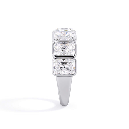A picture of a seven stone diamond wedding ring with radiant cut diamonds that are bezel set in white gold or platinum on a white background with a side profile view.