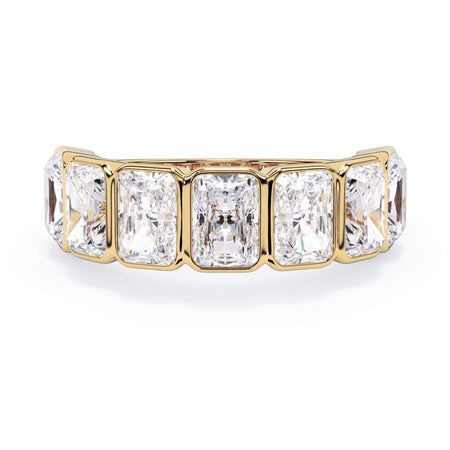 A picture of a seven stone diamond wedding ring with radiant cut diamonds that are bezel set in yellow gold on a white background with the ring facing forward, lying down.