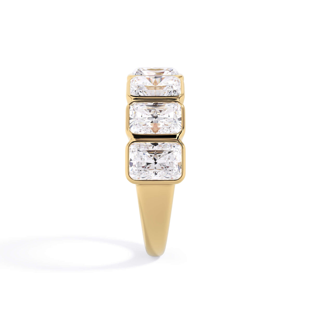 A picture of a seven stone diamond wedding ring with radiant cut diamonds that are bezel set in yellow gold on a white background with a side profile view.