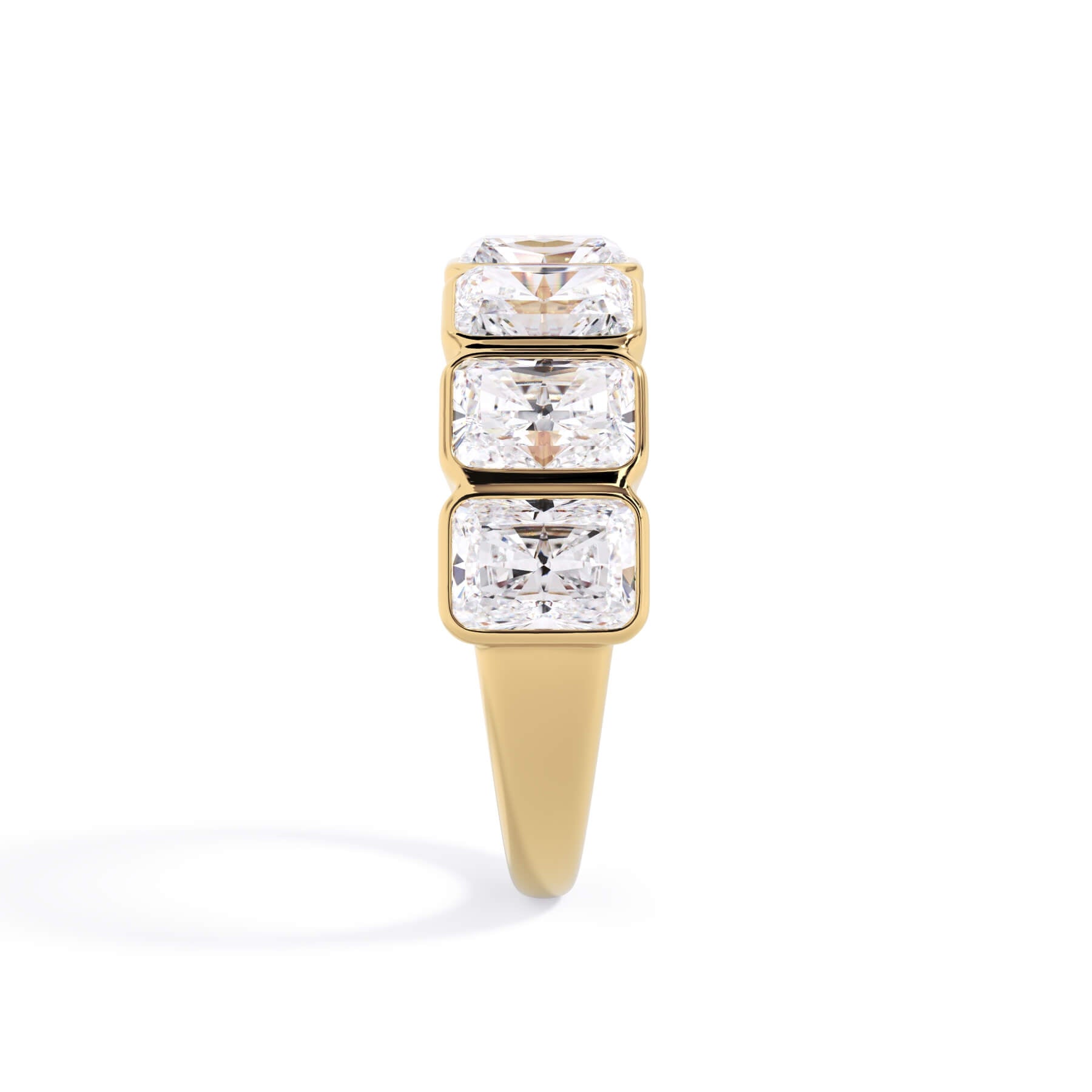 A picture of a seven stone diamond wedding ring with radiant cut diamonds that are bezel set in yellow gold on a white background with a side profile view.