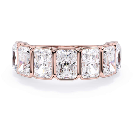 A picture of a seven stone diamond wedding ring with radiant cut diamonds that are bezel set in rose gold on a white background with the ring facing forward, lying down.