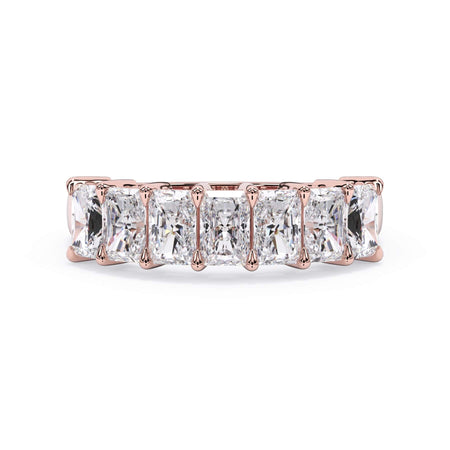 A picture of a seven stone diamond wedding ring with radiant cut diamonds that are shared prong set in rose gold on a white background with the ring facing forward, lying down.