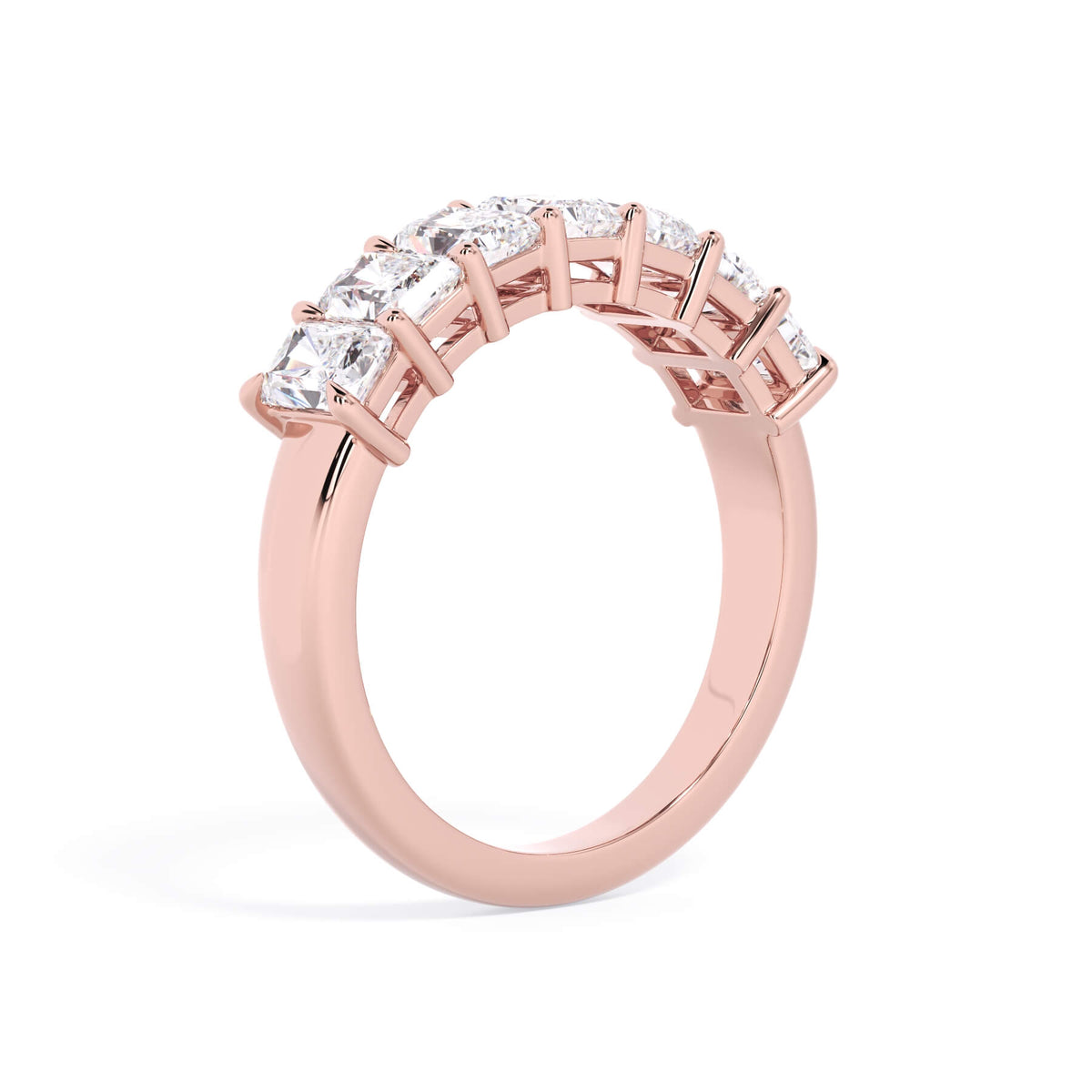 A picture of a seven stone diamond wedding ring with radiant cut diamonds that are shared prong set in rose gold on a white background with a slightly angled, through the finger view.