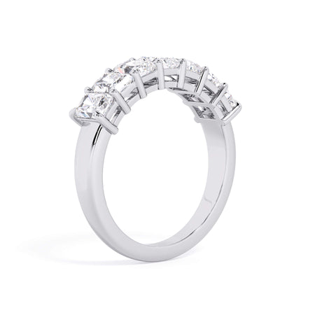 A picture of a seven stone diamond wedding ring with radiant cut diamonds that are shared prong set in white gold or platinum on a white background with a slightly angled, through the finger view.
