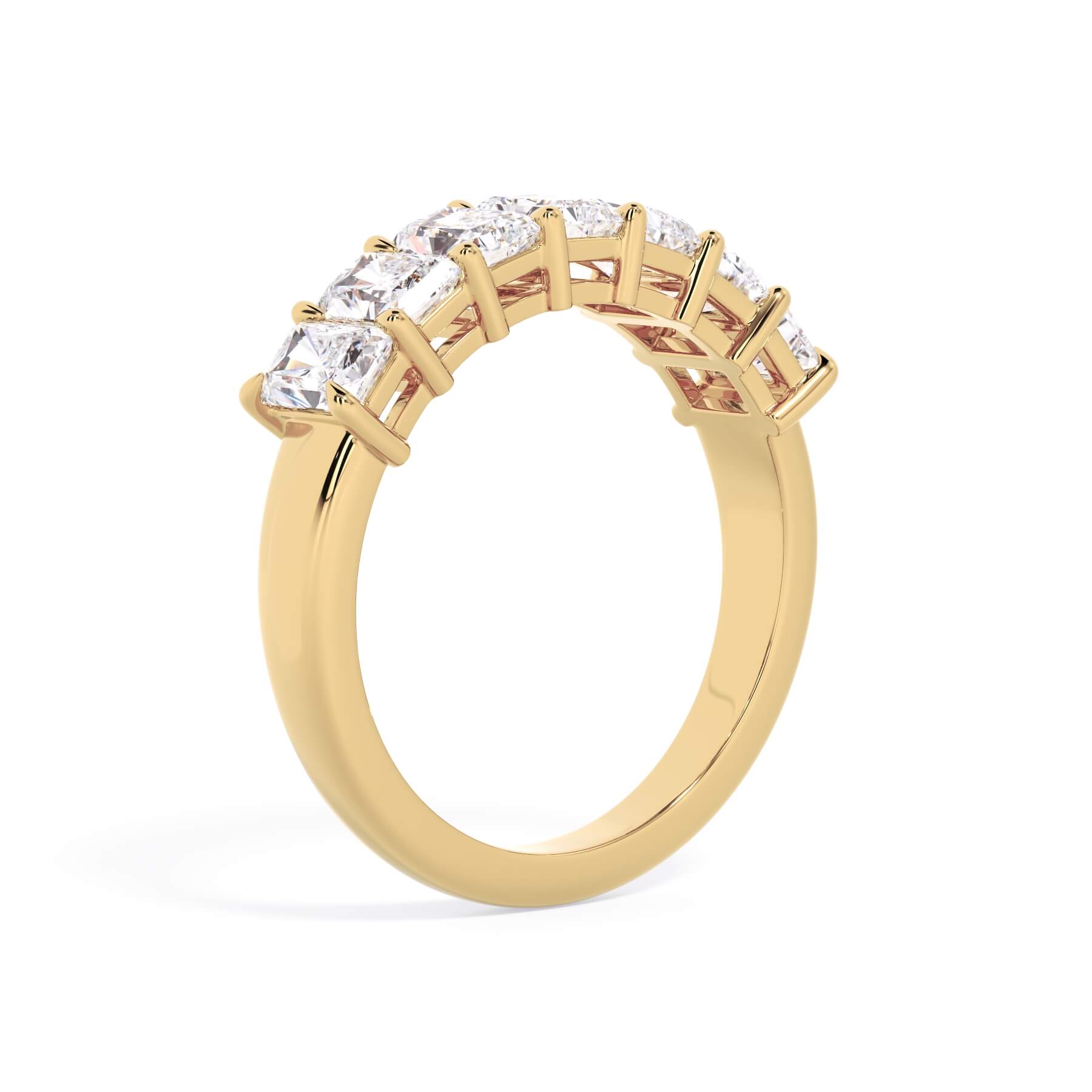 A picture of a seven stone diamond wedding ring with radiant cut diamonds that are shared prong set in yellow gold on a white background with a slightly angled, through the finger view.