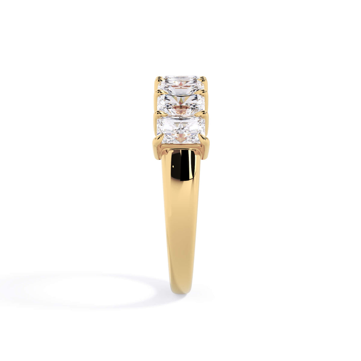 A picture of a seven stone diamond wedding ring with radiant cut diamonds that are shared prong set in yellow gold on a white background with a side profile view.