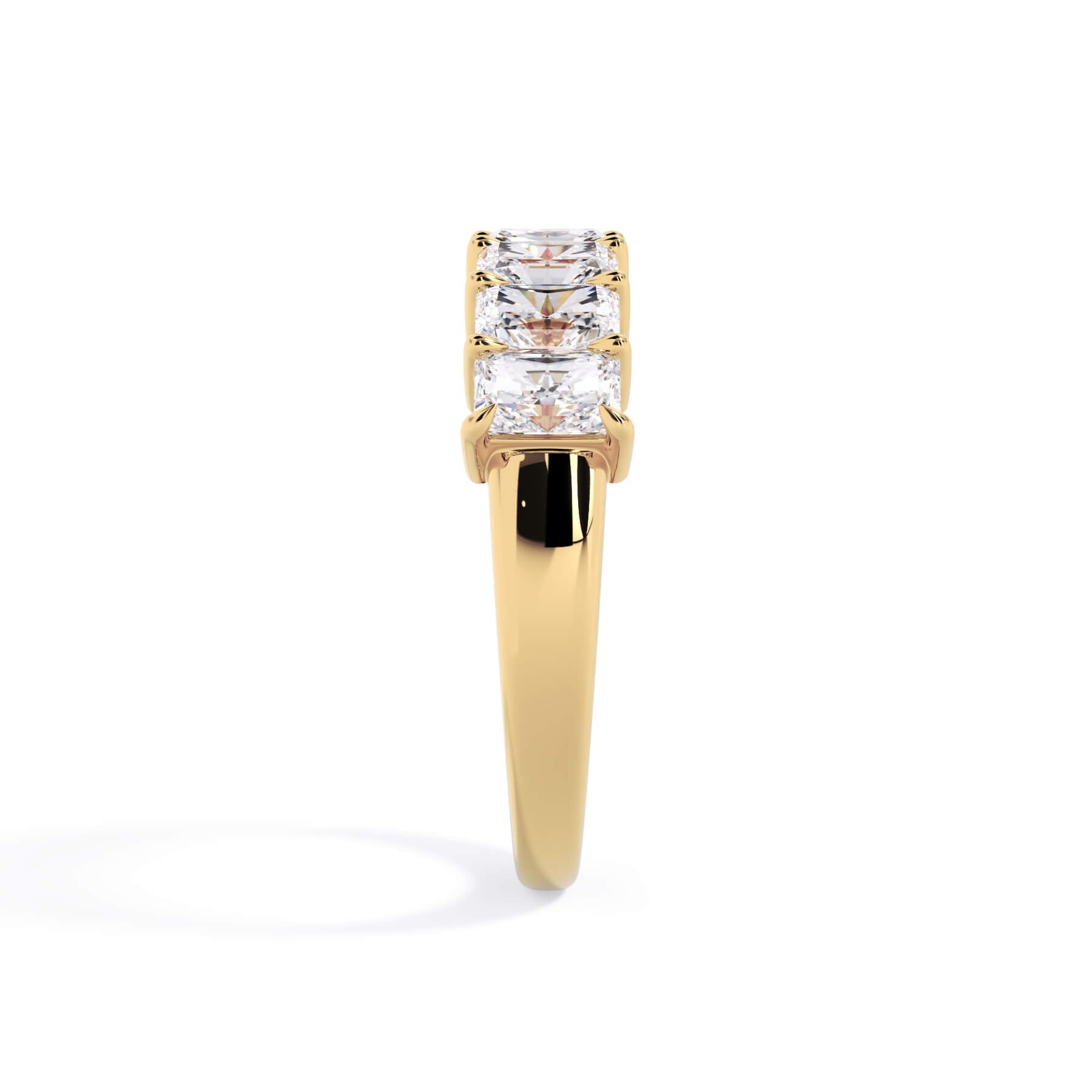 A picture of a seven stone diamond wedding ring with radiant cut diamonds that are shared prong set in yellow gold on a white background with a side profile view.