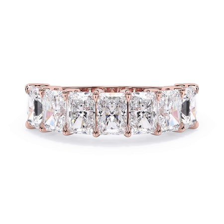 A picture of a seven stone diamond wedding ring with radiant cut diamonds that are shared prong set in rose gold on a white background with the ring facing forward, lying down.
