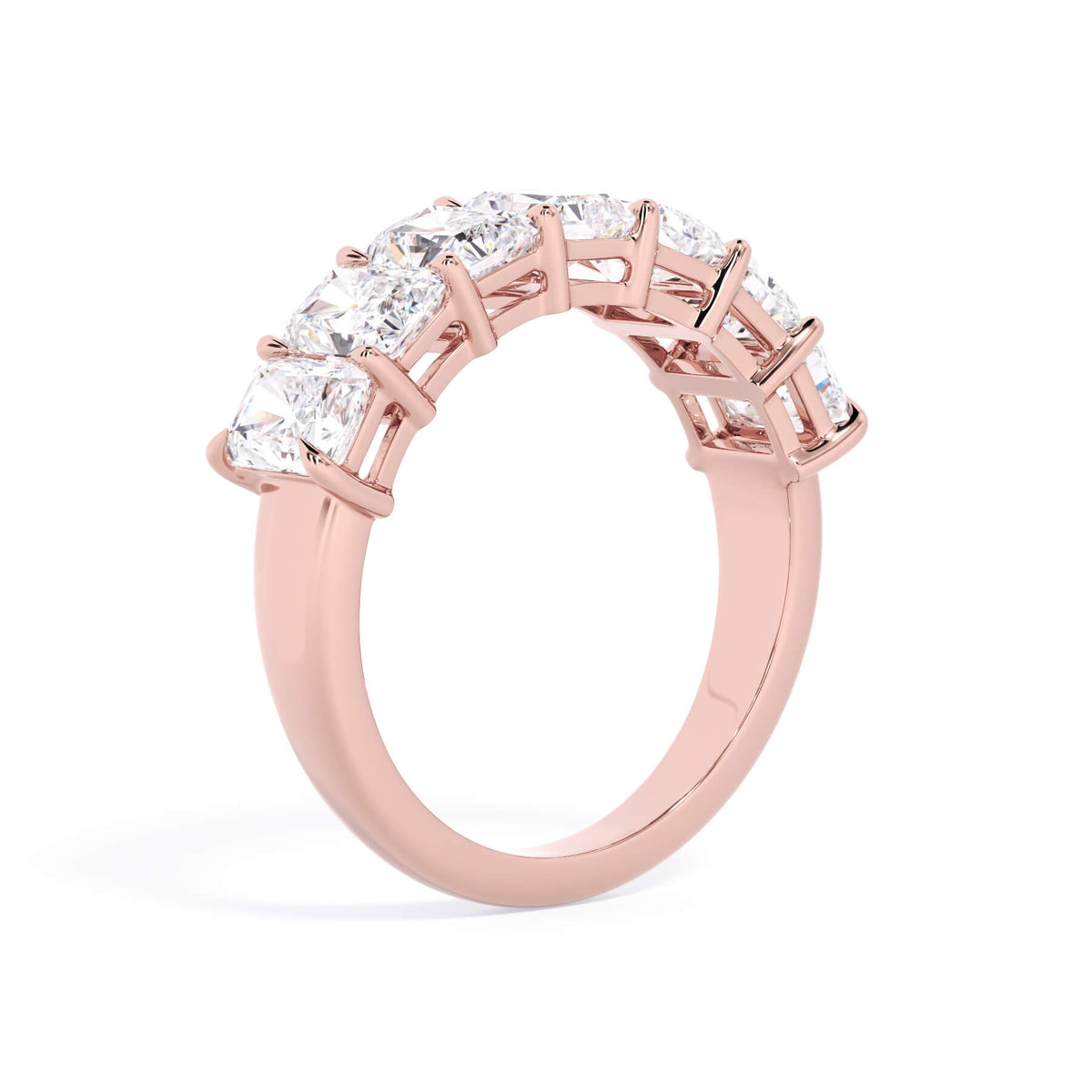 A picture of a seven stone diamond wedding ring with radiant cut diamonds that are shared prong set in rose gold on a white background with a slightly angled, through the finger view.