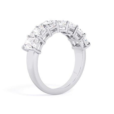 A picture of a seven stone diamond wedding ring with radiant cut diamonds that are shared prong set in white gold or platinum on a white background with a slightly angled, through the finger view.