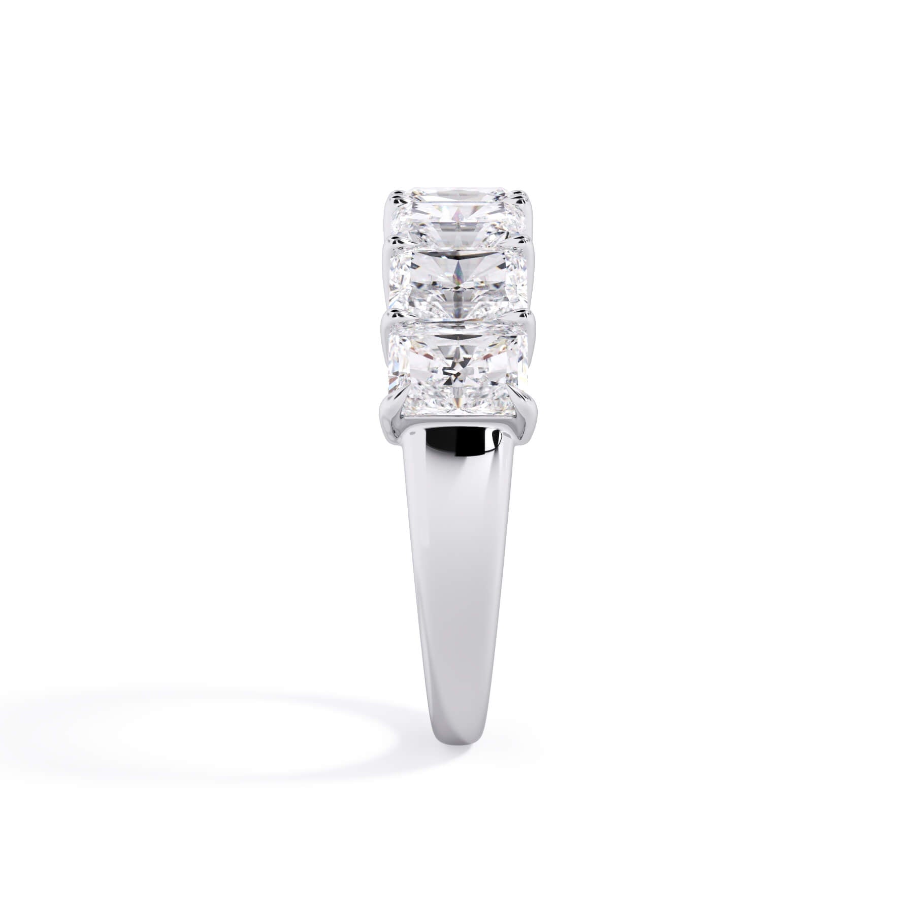 A picture of a seven stone diamond wedding ring with radiant cut diamonds that are shared prong set in white gold or platinum on a white background with a side profile view.