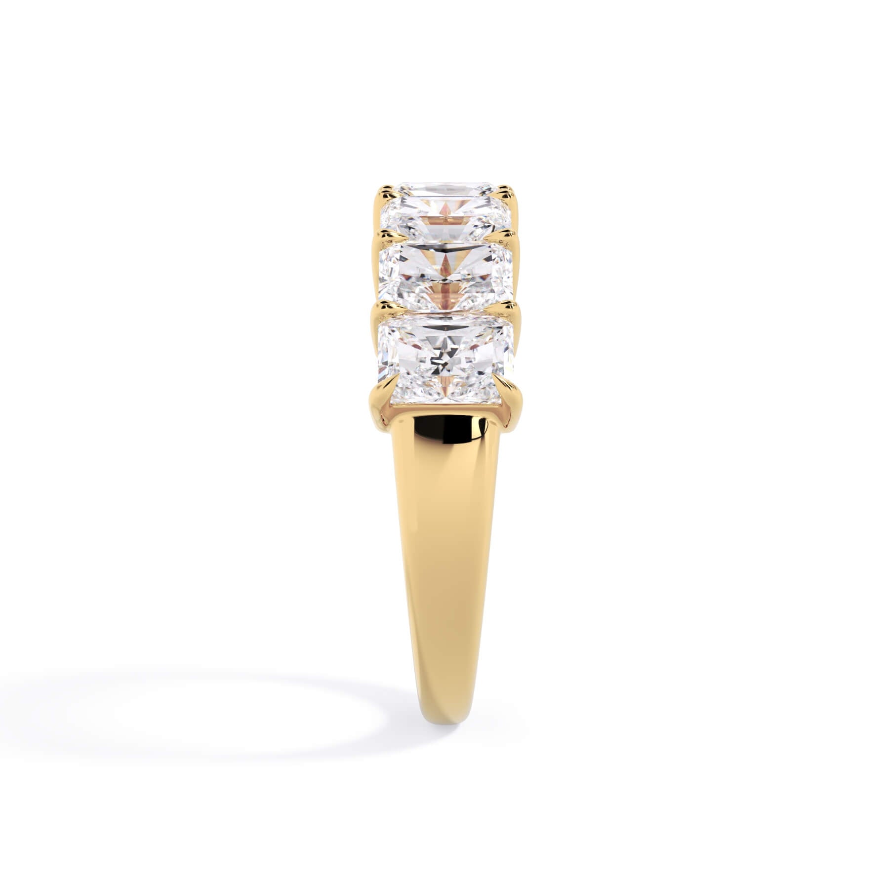 A picture of a seven stone diamond wedding ring with radiant cut diamonds that are shared prong set in yellow gold on a white background with a side profile view.
