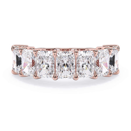 A picture of a seven stone diamond wedding ring with radiant cut diamonds that are shared prong set in rose gold on a white background with the ring facing forward, lying down.