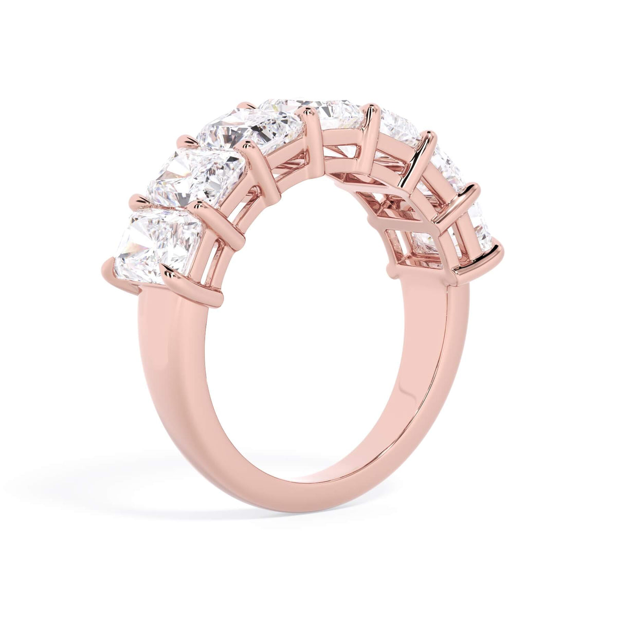 A picture of a seven stone diamond wedding ring with radiant cut diamonds that are shared prong set in rose gold on a white background with a slightly angled, through the finger view.