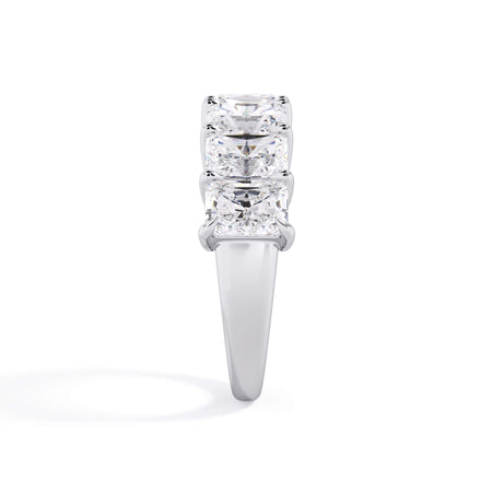 A picture of a seven stone diamond wedding ring with radiant cut diamonds that are shared prong set in white gold or platinum on a white background with a side profile view.