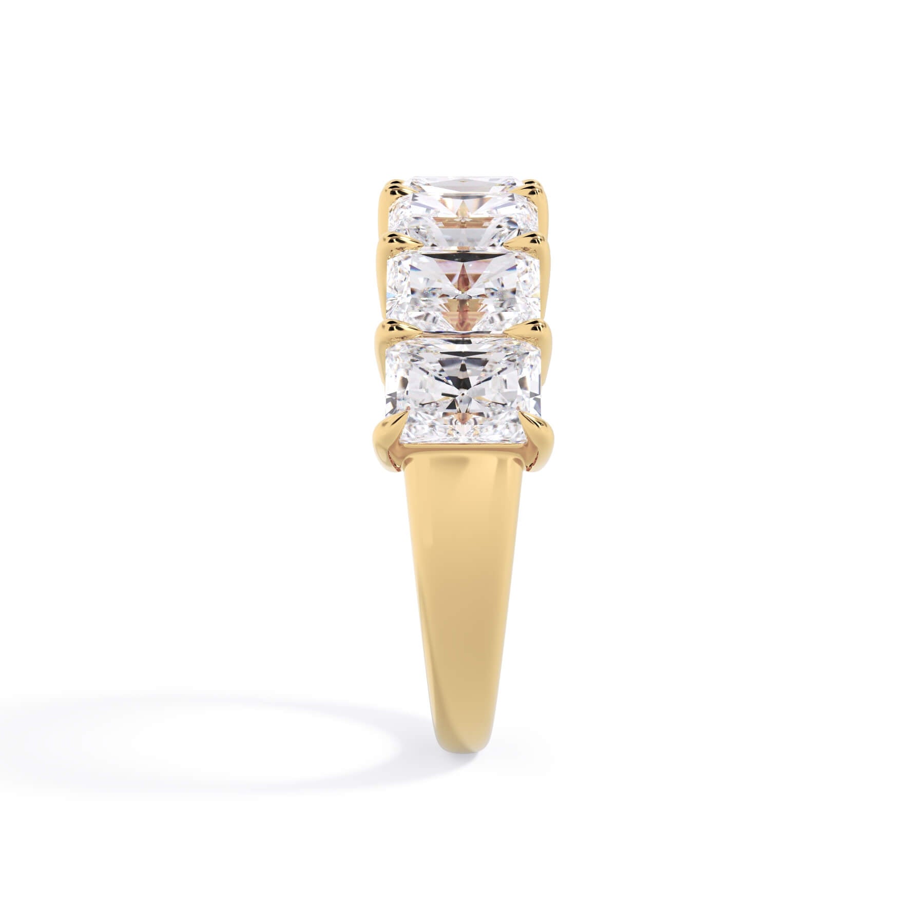 A picture of a seven stone diamond wedding ring with radiant cut diamonds that are shared prong set in yellow gold on a white background with a side profile view.