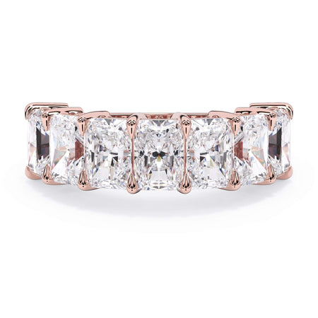 A picture of a seven stone diamond wedding ring with radiant cut diamonds that are shared prong set in rose gold on a white background with the ring facing forward, lying down.