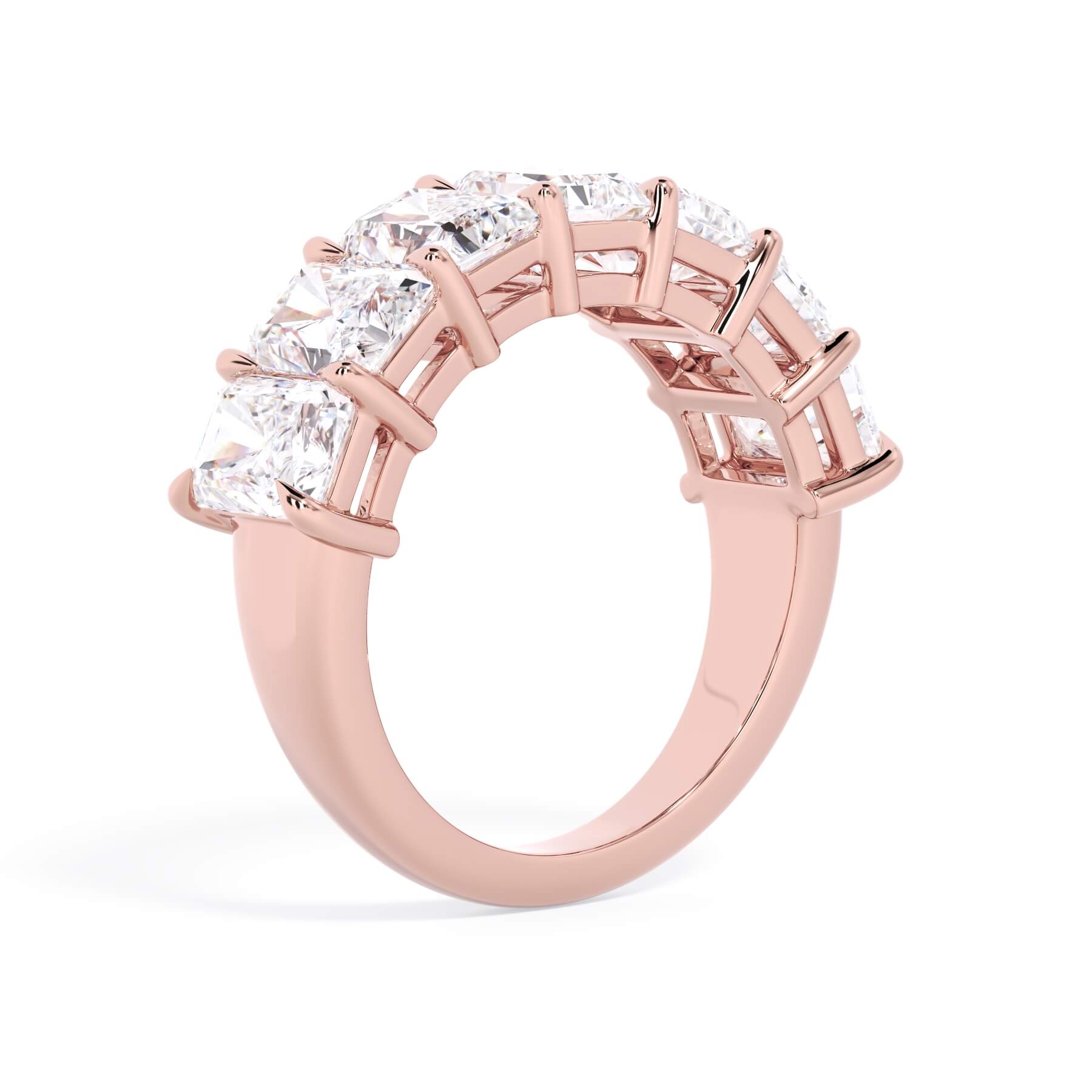 A picture of a seven stone diamond wedding ring with radiant cut diamonds that are shared prong set in rose gold on a white background with a slightly angled, through the finger view.