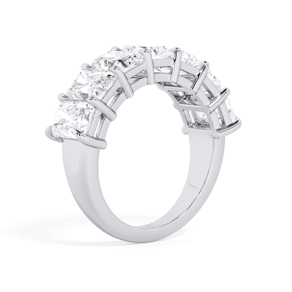 A picture of a seven stone diamond wedding ring with radiant cut diamonds that are shared prong set in white gold or platinum on a white background with a slightly angled, through the finger view.