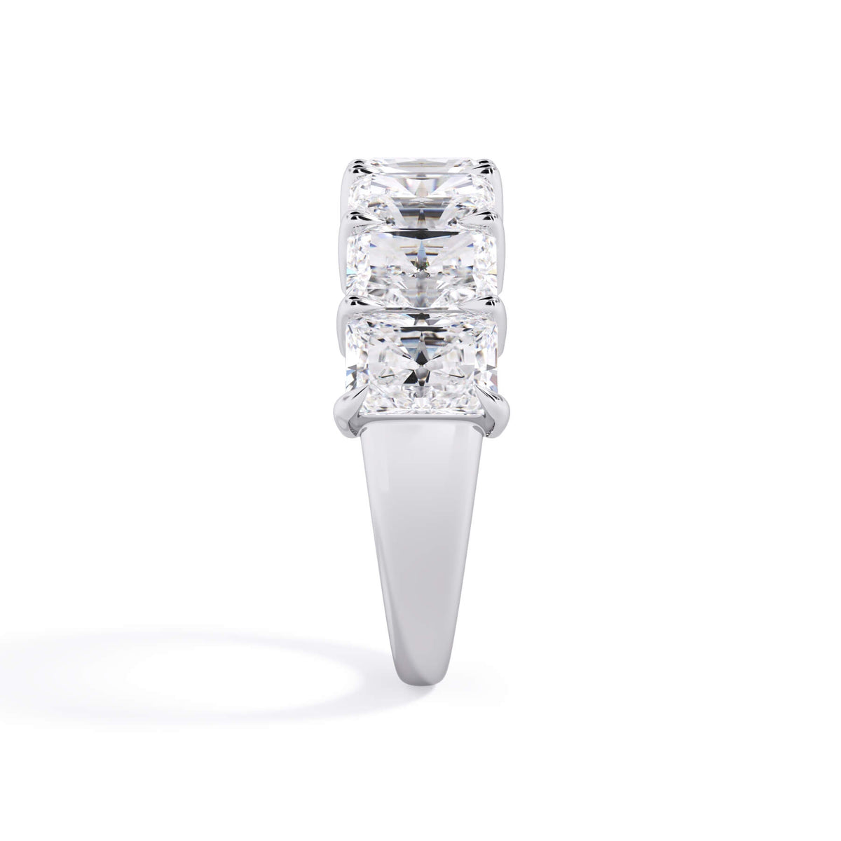A picture of a seven stone diamond wedding ring with radiant cut diamonds that are shared prong set in white gold or platinum on a white background with a side profile view.