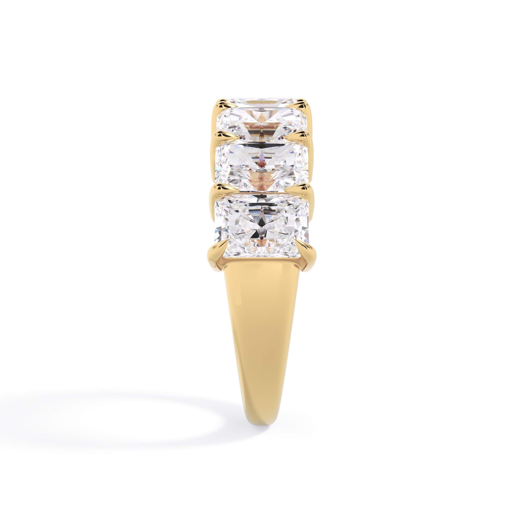 A picture of a seven stone diamond wedding ring with radiant cut diamonds that are shared prong set in yellow gold on a white background with a side profile view.