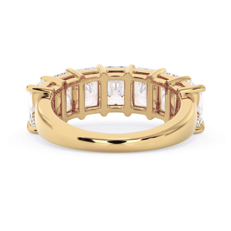 A picture of a seven stone diamond wedding ring with radiant cut diamonds that are shared prong set in yellow gold on a white background with a view of the underside of the ring.