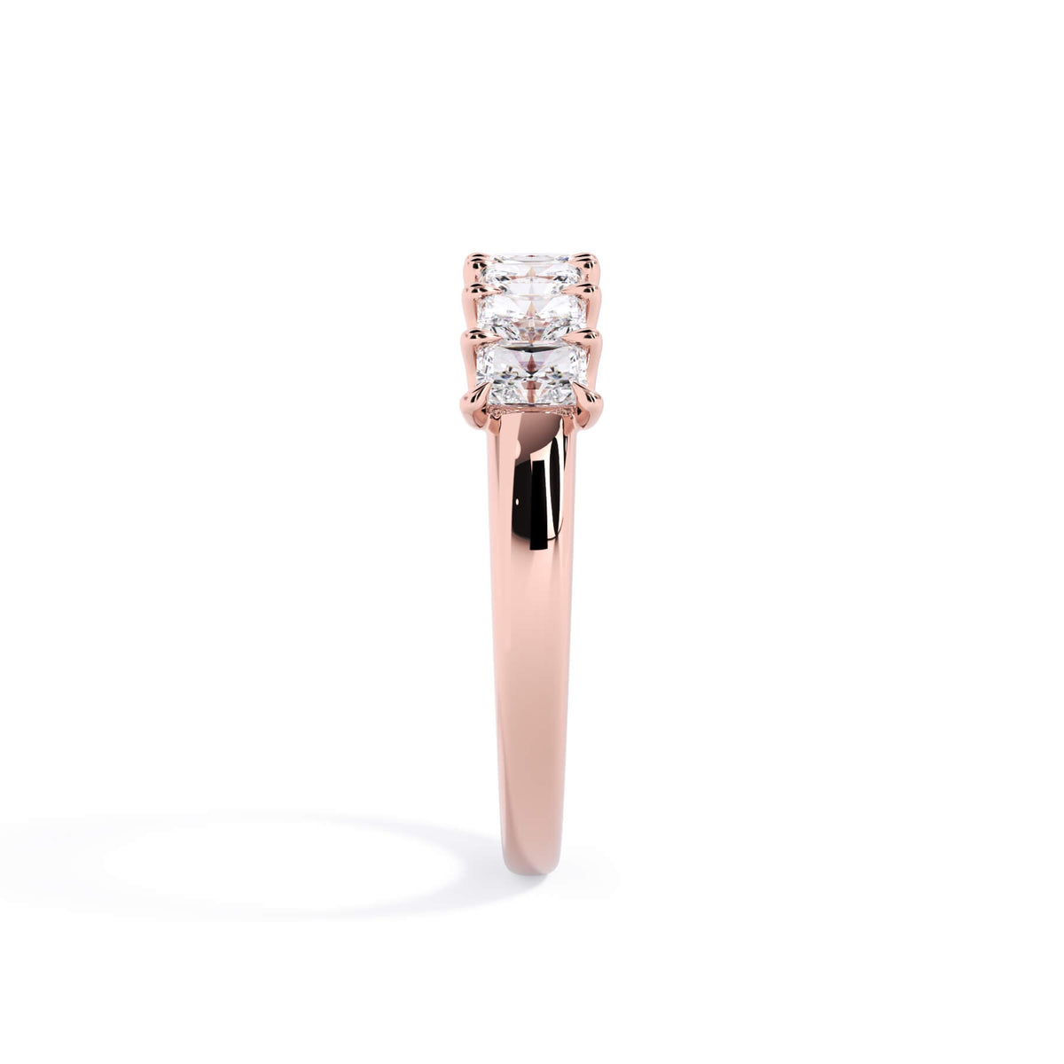 A picture of a seven stone diamond wedding ring with radiant cut diamonds that are U prong set in rose gold on a white background with a side profile view.