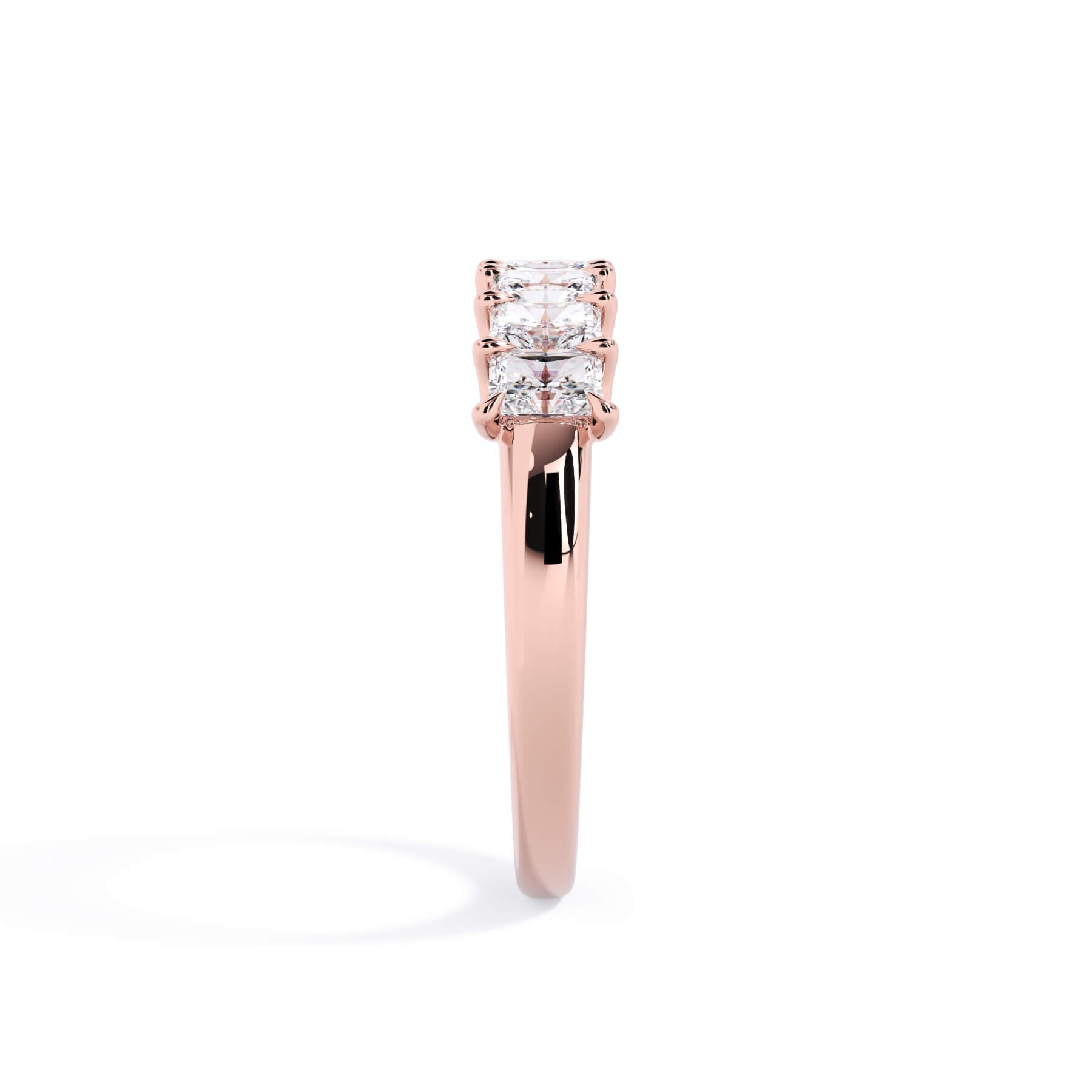 A picture of a seven stone diamond wedding ring with radiant cut diamonds that are U prong set in rose gold on a white background with a side profile view.
