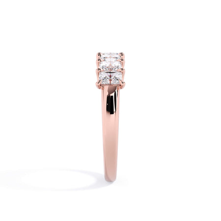 A picture of a seven stone diamond wedding ring with radiant cut diamonds that are U prong set in rose gold on a white background with a side profile view.