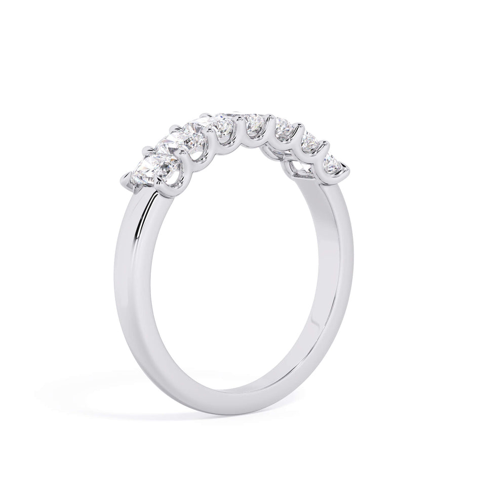 A picture of a seven stone diamond wedding ring with radiant cut diamonds that are U prong set in white gold or platinum on a white background with a slightly angled, through the finger view.