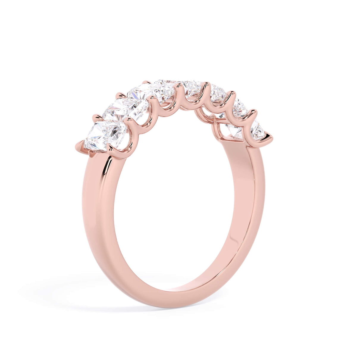 A picture of a seven stone diamond wedding ring with radiant cut diamonds that are U prong set in rose gold on a white background with a slightly angled, through the finger view.