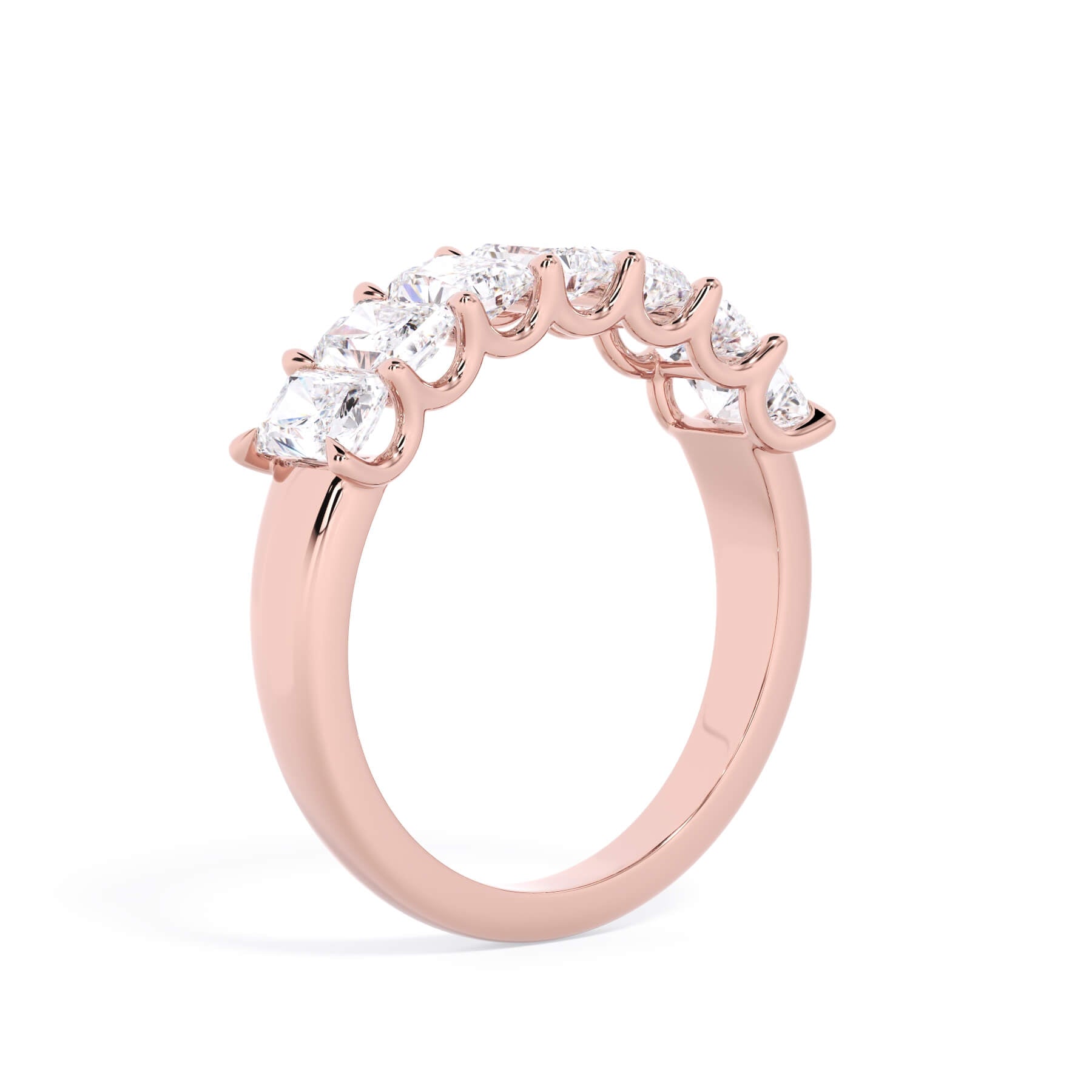 A picture of a seven stone diamond wedding ring with radiant cut diamonds that are U prong set in rose gold on a white background with a slightly angled, through the finger view.