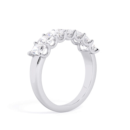 A picture of a seven stone diamond wedding ring with radiant cut diamonds that are U prong set in white gold or platinum on a white background with a slightly angled, through the finger view.