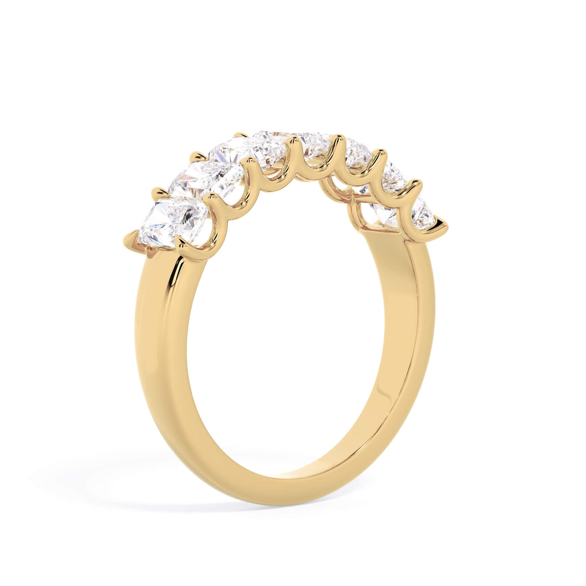 A picture of a seven stone diamond wedding ring with radiant cut diamonds that are U prong set in yellow gold on a white background with a slightly angled, through the finger view.
