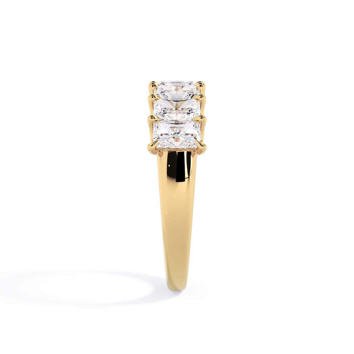 A picture of a seven stone diamond wedding ring with radiant cut diamonds that are U prong set in yellow gold on a white background with a side profile view.